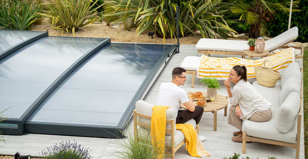 Abri de piscine bas Charline fermé, au bord d’une terrasse où un couple prend un brunch au soleil